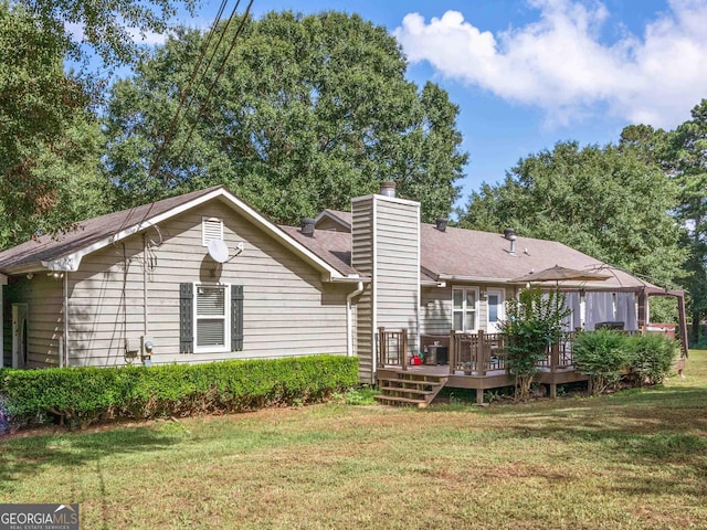 rear view of property with a chimney, a lawn, and a deck