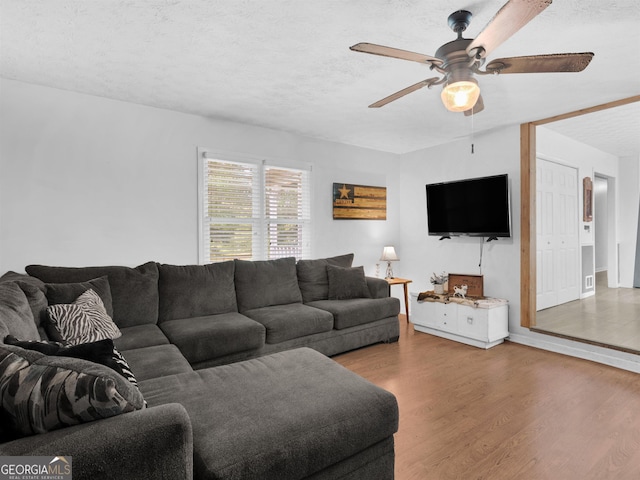 living room with ceiling fan, a textured ceiling, and wood finished floors