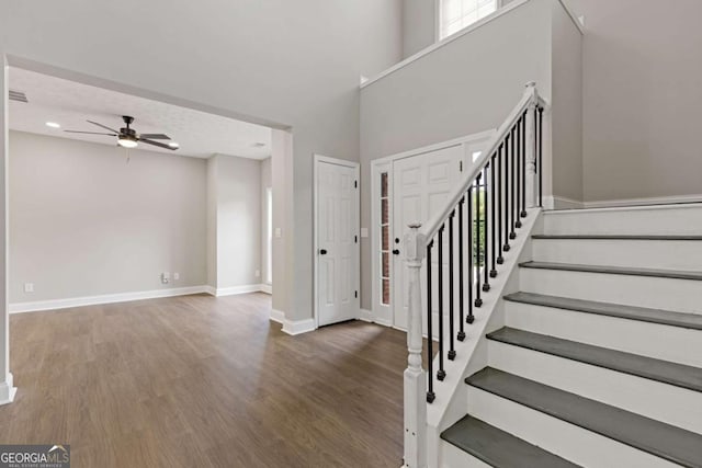 foyer entrance featuring ceiling fan, dark hardwood / wood-style flooring, and a high ceiling