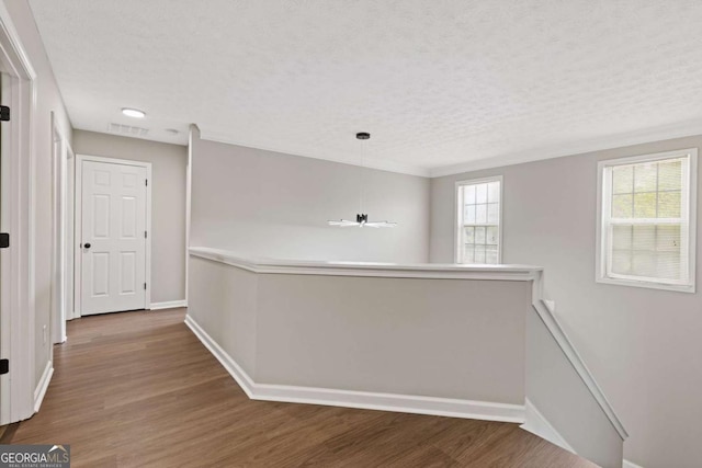 corridor with a textured ceiling and dark hardwood / wood-style floors