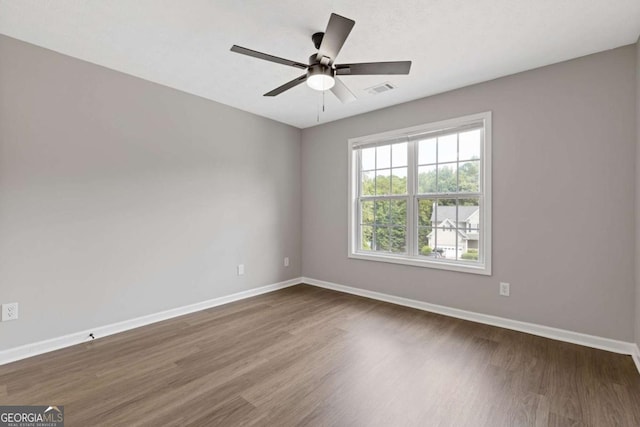 empty room with ceiling fan and dark hardwood / wood-style flooring