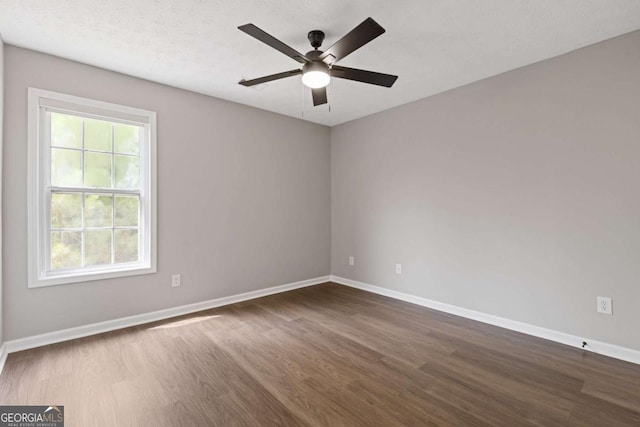 empty room with ceiling fan and dark hardwood / wood-style flooring