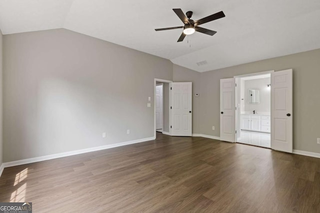 interior space featuring ceiling fan, ensuite bathroom, dark wood-type flooring, and lofted ceiling