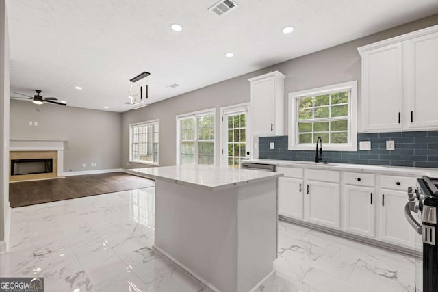 kitchen with tasteful backsplash, ceiling fan, pendant lighting, stainless steel range oven, and white cabinetry