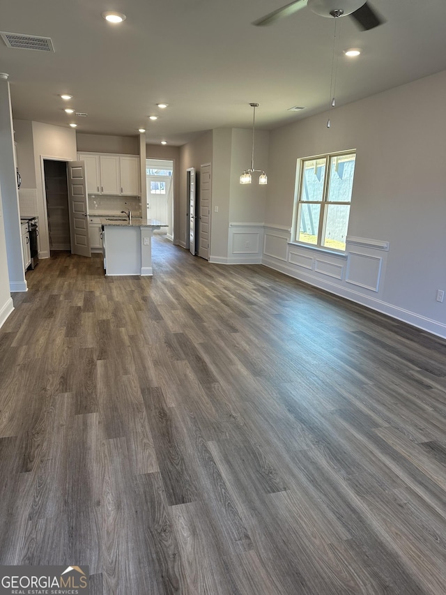 unfurnished living room with dark wood-style floors, a wealth of natural light, and visible vents