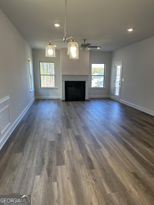 unfurnished living room featuring dark wood-type flooring, a fireplace with flush hearth, ceiling fan, and baseboards