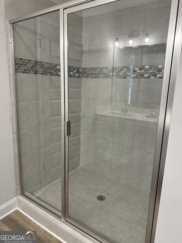 full bath featuring a stall shower and wood finished floors