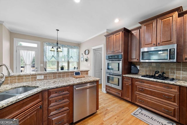 kitchen with sink, light stone countertops, light wood-type flooring, stainless steel appliances, and a chandelier