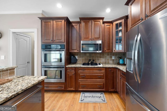 kitchen featuring light stone countertops, stainless steel appliances, tasteful backsplash, and crown molding