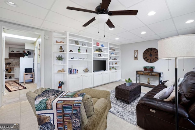 living room featuring a drop ceiling, ceiling fan, light tile patterned flooring, and built in shelves