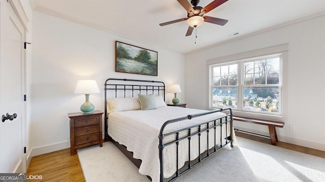 bedroom with light hardwood / wood-style floors, ceiling fan, and ornamental molding