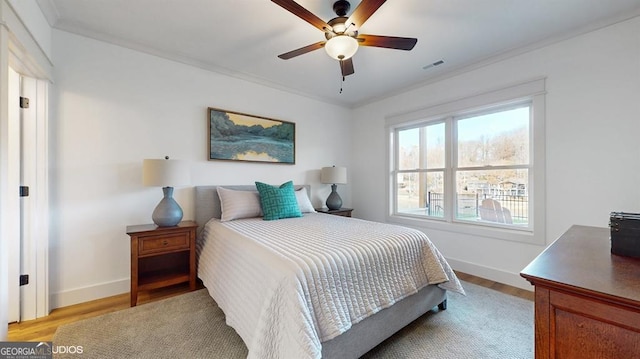 bedroom with ceiling fan, crown molding, and light hardwood / wood-style flooring