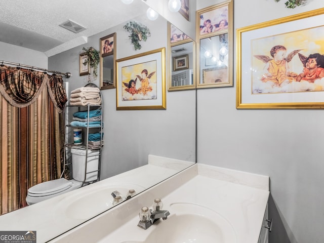 bathroom featuring vanity, a textured ceiling, and toilet