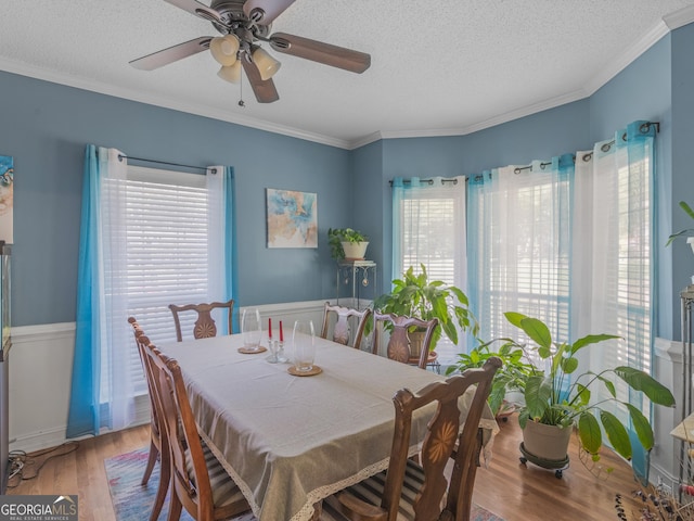 dining space with hardwood / wood-style floors, a textured ceiling, ceiling fan, and ornamental molding