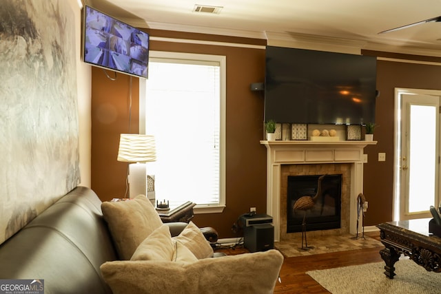 living area with a fireplace, wood-type flooring, and ornamental molding