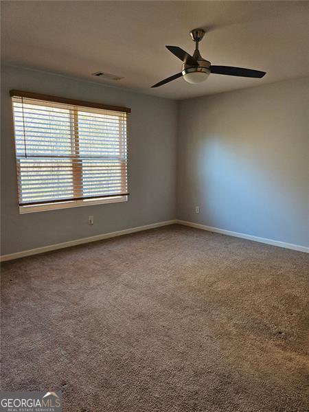 carpeted spare room featuring ceiling fan