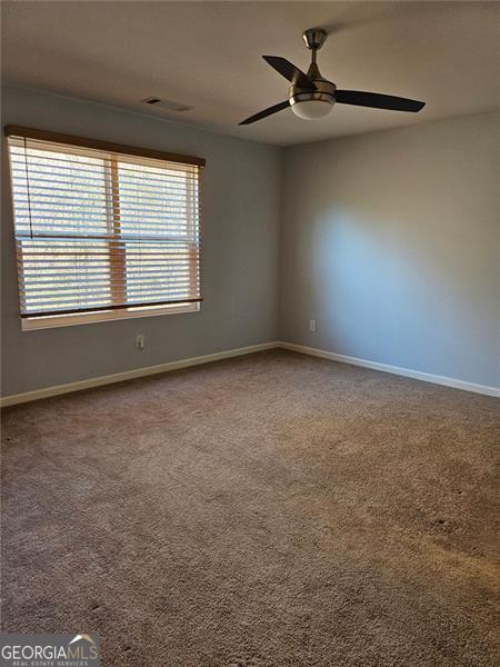 unfurnished room with a wealth of natural light, carpet, and ceiling fan