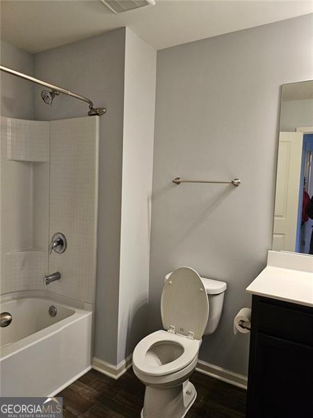 full bathroom with hardwood / wood-style flooring, vanity, toilet, and shower / bath combination