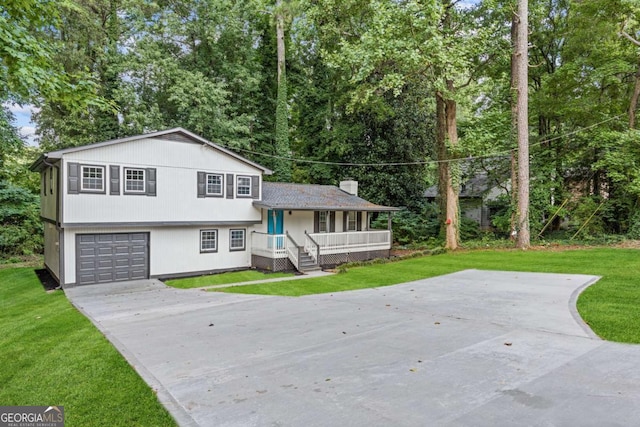 split level home with covered porch, a garage, and a front yard