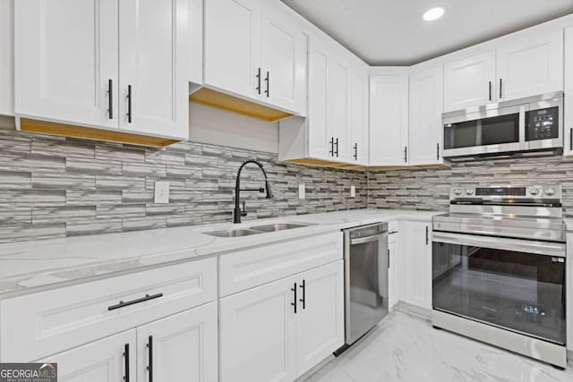 kitchen with light stone counters, sink, white cabinets, and appliances with stainless steel finishes