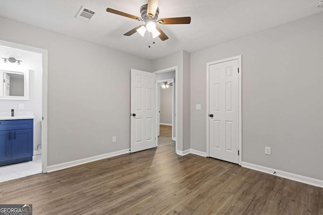 unfurnished bedroom featuring ensuite bathroom, ceiling fan, and dark hardwood / wood-style floors