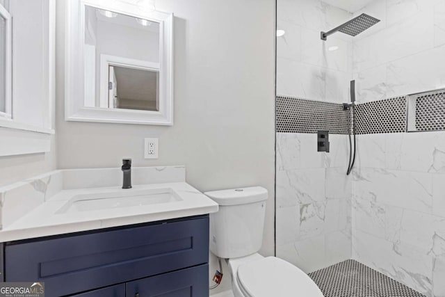 bathroom featuring vanity, toilet, and a tile shower