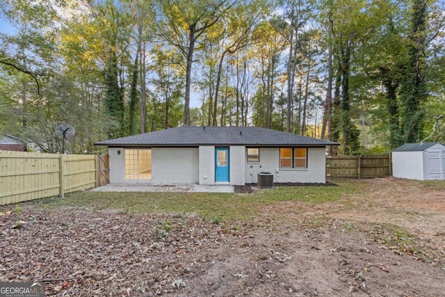 rear view of property with central AC unit and a shed