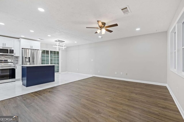 unfurnished living room with ceiling fan, hardwood / wood-style floors, and a textured ceiling