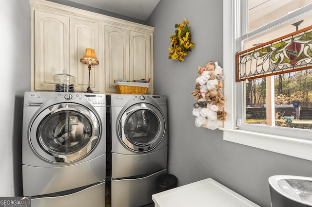 clothes washing area with washing machine and clothes dryer and cabinets