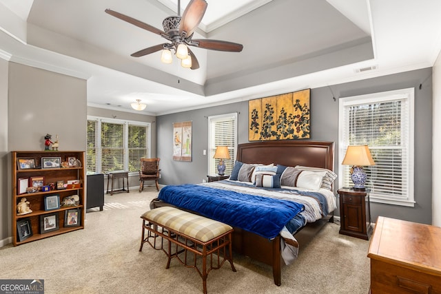 carpeted bedroom with a raised ceiling, multiple windows, ceiling fan, and crown molding