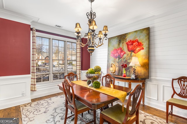 dining area featuring light hardwood / wood-style floors, crown molding, and an inviting chandelier