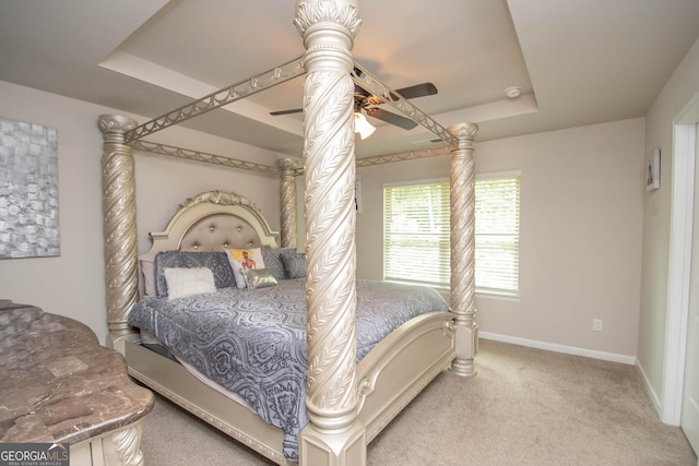 carpeted bedroom featuring ceiling fan and a raised ceiling