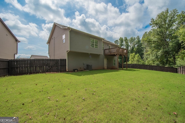 rear view of property featuring a yard, central AC unit, and a wooden deck