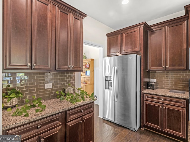 kitchen featuring backsplash, dark wood-type flooring, stainless steel refrigerator with ice dispenser, dark brown cabinets, and light stone counters