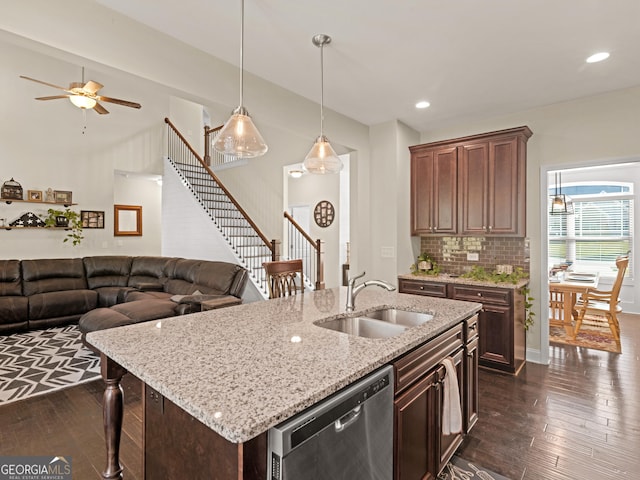 kitchen with sink, hanging light fixtures, tasteful backsplash, stainless steel dishwasher, and a kitchen island with sink