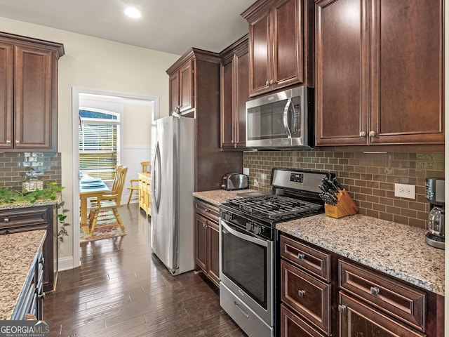 kitchen featuring backsplash, stainless steel appliances, light stone counters, and dark brown cabinetry