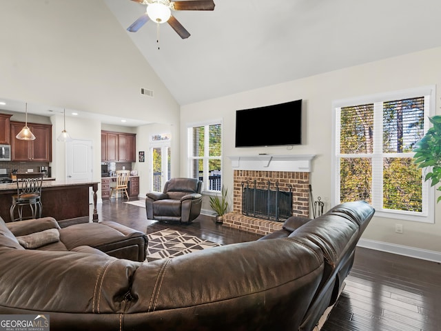 living room featuring a wealth of natural light, high vaulted ceiling, dark hardwood / wood-style floors, and ceiling fan