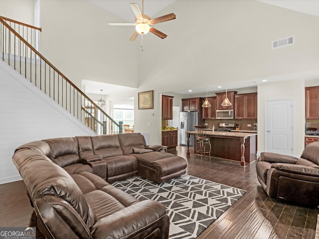 living room with ceiling fan with notable chandelier and high vaulted ceiling