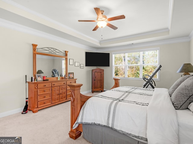 carpeted bedroom with a tray ceiling, ceiling fan, and ornamental molding