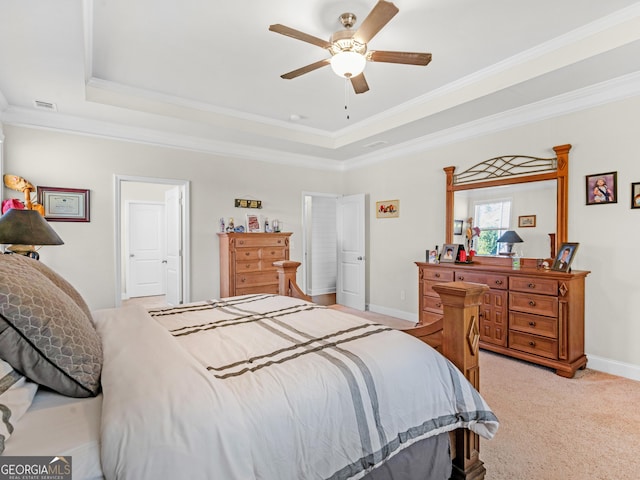 carpeted bedroom with ceiling fan, a raised ceiling, and ornamental molding