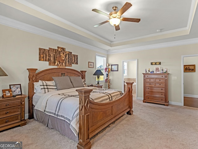 carpeted bedroom featuring ceiling fan, a raised ceiling, crown molding, and connected bathroom