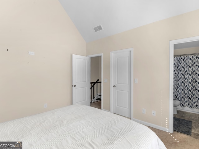 bedroom featuring ensuite bathroom, light colored carpet, and vaulted ceiling