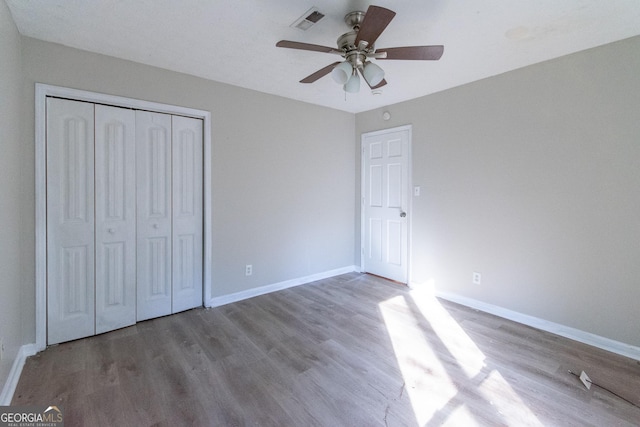 unfurnished bedroom with hardwood / wood-style floors, ceiling fan, and a closet