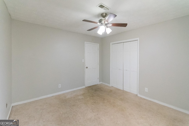 unfurnished bedroom with light colored carpet, a closet, and ceiling fan