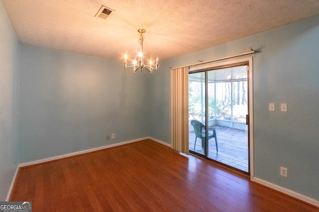 spare room featuring hardwood / wood-style flooring, a chandelier, and a textured ceiling