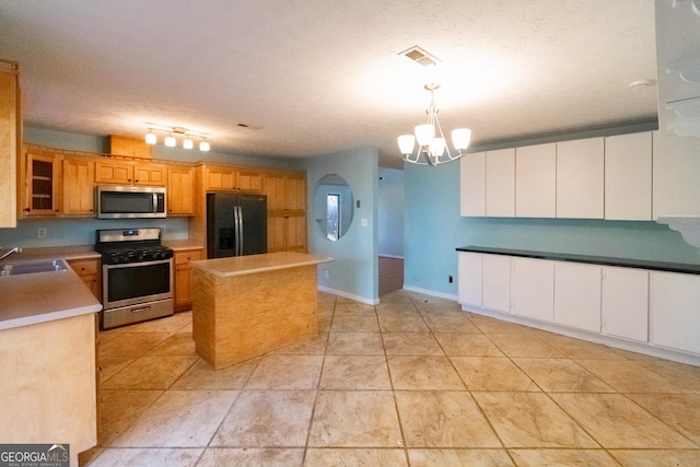 kitchen featuring sink, appliances with stainless steel finishes, an inviting chandelier, a kitchen island, and decorative light fixtures