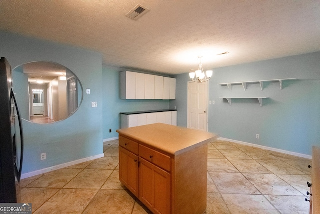 kitchen with pendant lighting, white cabinets, fridge, a center island, and an inviting chandelier