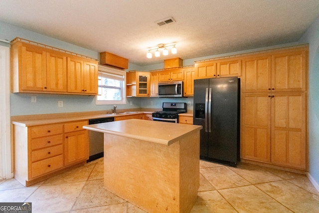 kitchen featuring rail lighting, sink, a center island, a textured ceiling, and stainless steel appliances