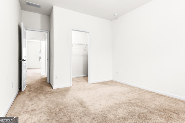 unfurnished bedroom featuring light colored carpet, a spacious closet, and a closet