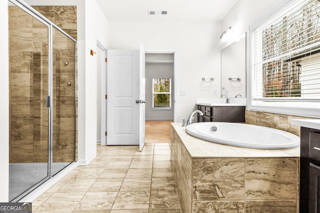 bathroom featuring a healthy amount of sunlight, vanity, and independent shower and bath